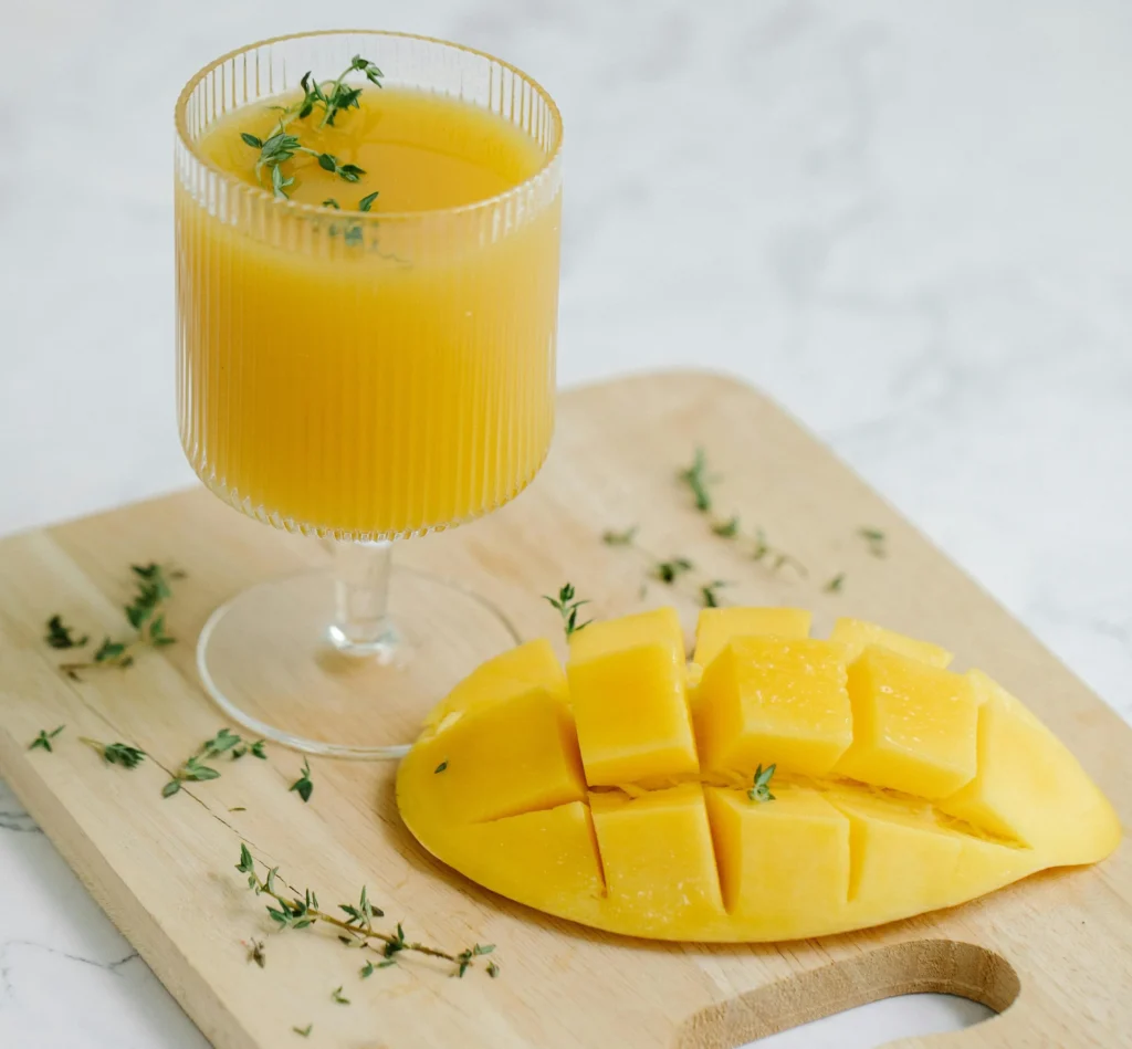 A Slice of Mango Fruit And Glass of Juice On Wooden Chopping Board