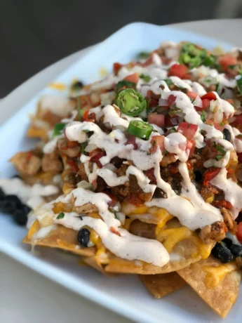 A colorful assortment of fresh vegetables including tomatoes, bell peppers, and avocados, used as toppings for the vegetarian nachos