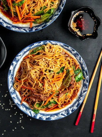 A serving platter of Chicken Lo Mein, showcasing the vibrant colors of the dish with a sprinkling of sesame seeds on top.