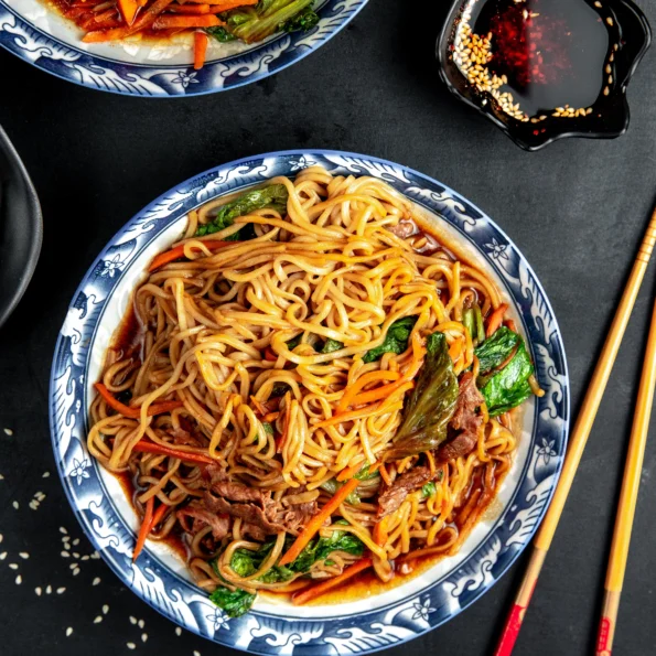 A serving platter of Chicken Lo Mein, showcasing the vibrant colors of the dish with a sprinkling of sesame seeds on top.