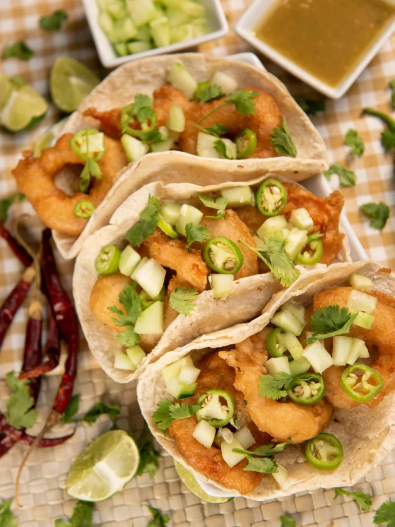 Close-up of seasoned chicken strips marinating in a bowl with spices and lime juice