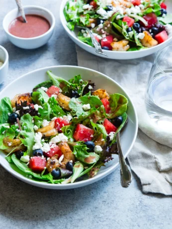 A bowl filled with colorful bell pepper slices, jalapeño slices, diced tomatoes, and sliced black olives