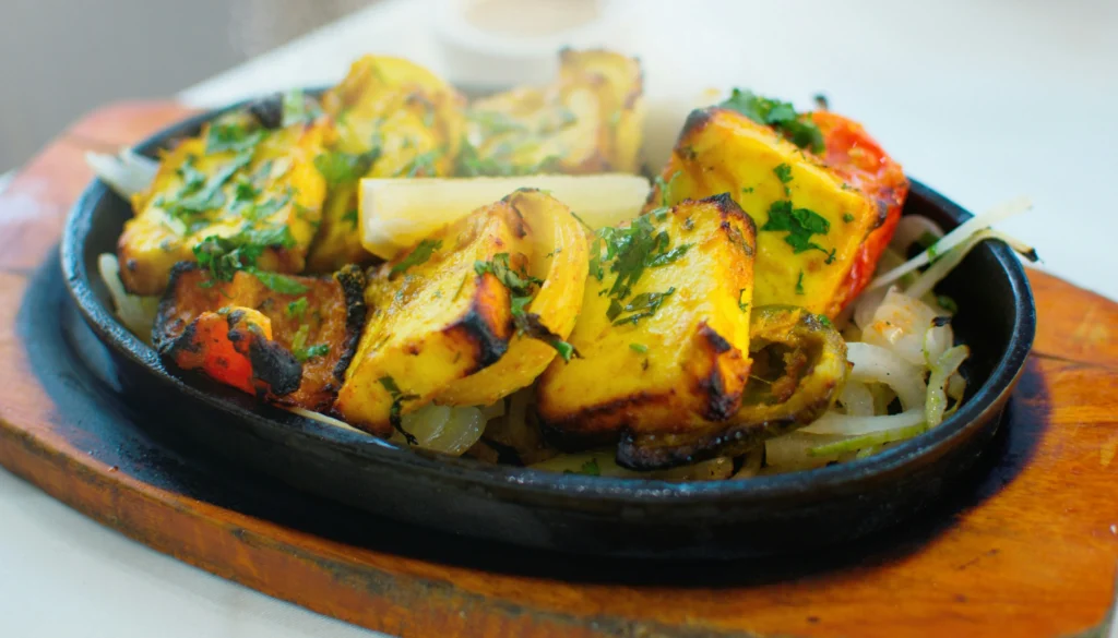 Golden brown paneer cubes sautéing in a pan