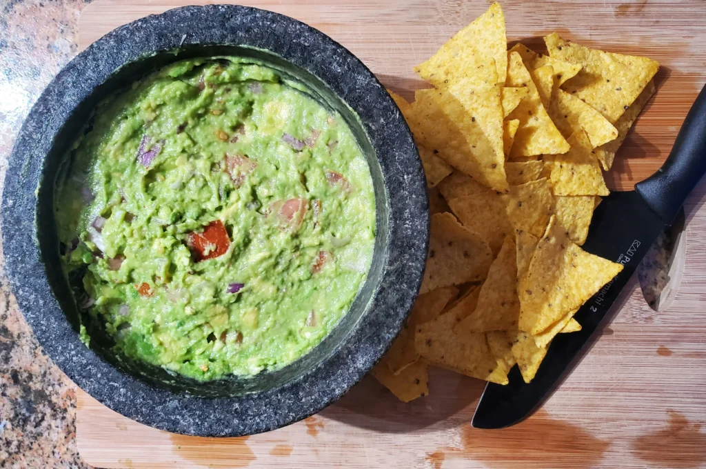 Stack of tortilla chips with salsa and guacamole