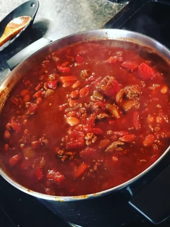 A bowl of Texas chili served in a rustic ceramic dish, topped with a swirl of sour cream