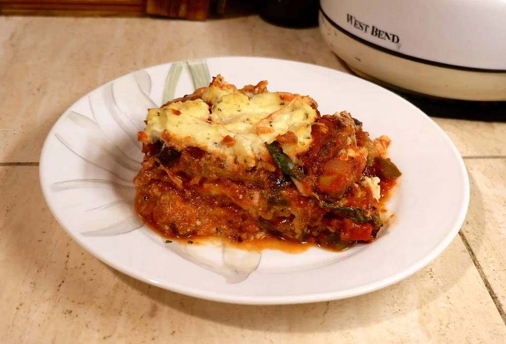 "Layers of baked eggplant, marinara sauce, and dairy-free cheese in a baking dish