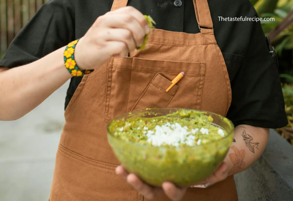 A Female Chef Squeezing a Lime to guacamole salsa