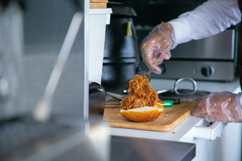 Cook putting fried pork on bun for burger