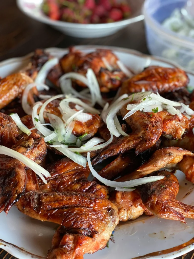 Cooked smoked Chicken Wings with White Sliced White Onion on Top on White Ceramic Plate