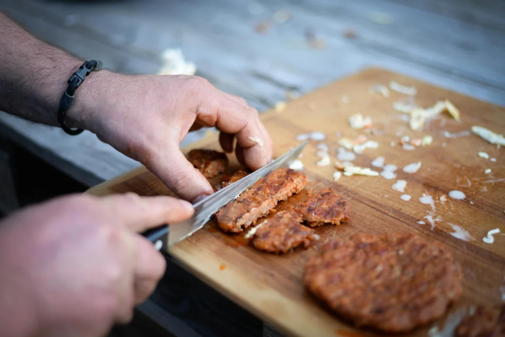 Crop man cutting burger patty on board