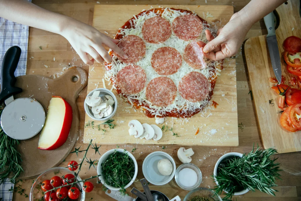 Crop people cooking homemade pizza together