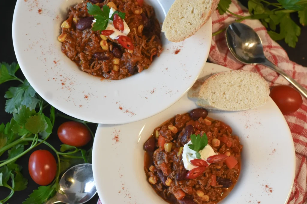 A spoonful of Texas chili being lifted out of a bowl, showcasing the rich and chunky texture of the dish, with steam rising from the bow