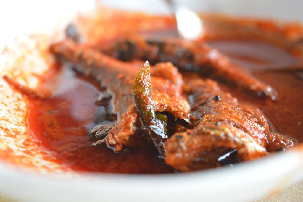 An overhead shot of a pot filled with simmering fish curry, showcasing the vibrant colors of the curry sauce and tender fish chunks