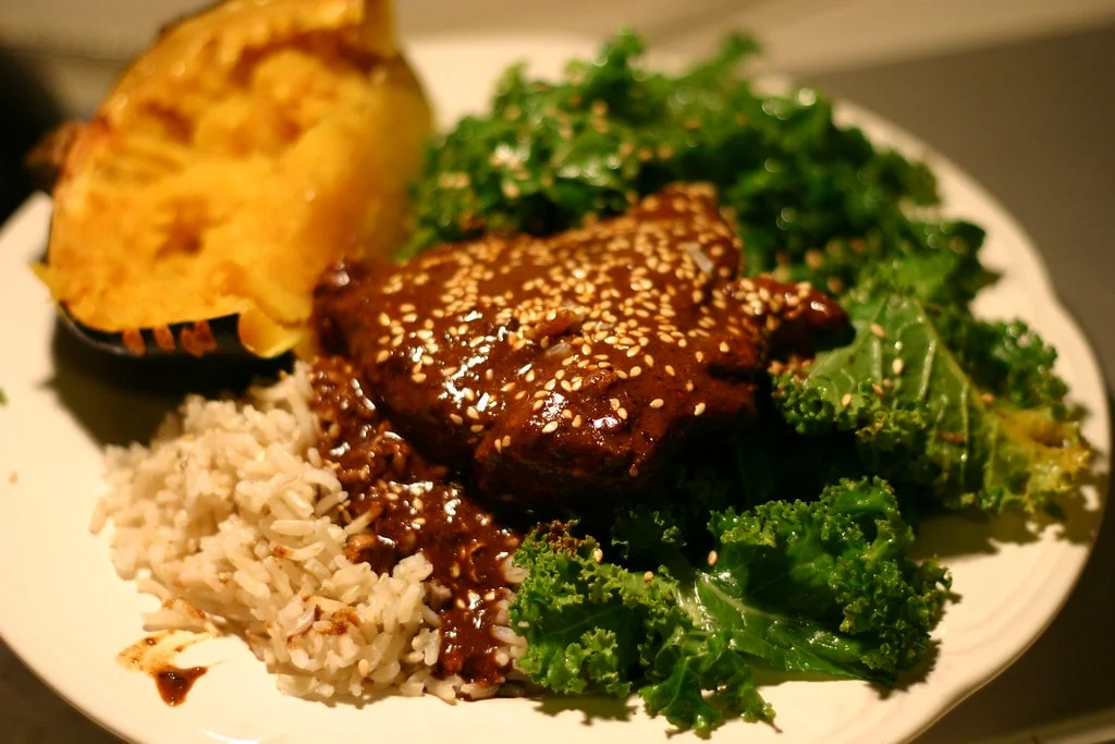 Cooking Mole Chicken: Chicken breasts searing in flavorful mole sauce in a skillet.