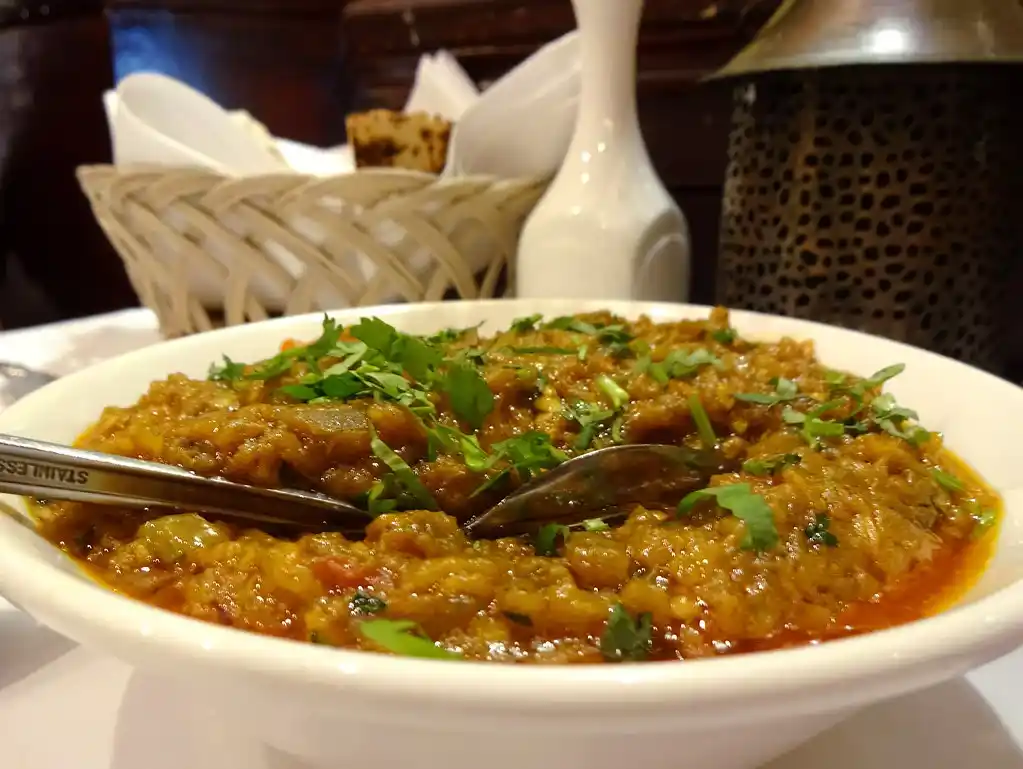 Eggplant being roasted over an open flame until the skin is charred for Baingan Bharta