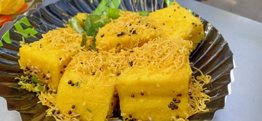 Beautifully plated Dhokla garnished with coconut and coriander, served with chutneys