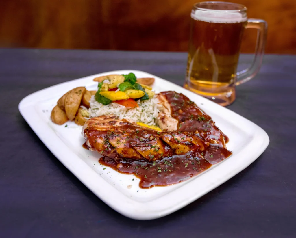 Delicious roasted mole chicken steak with potatoes and glass of beer