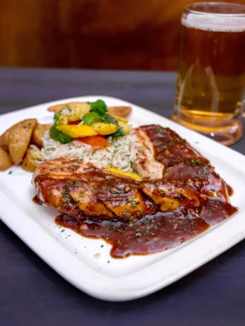 Delicious roasted mole chicken steak with potatoes and glass of beer