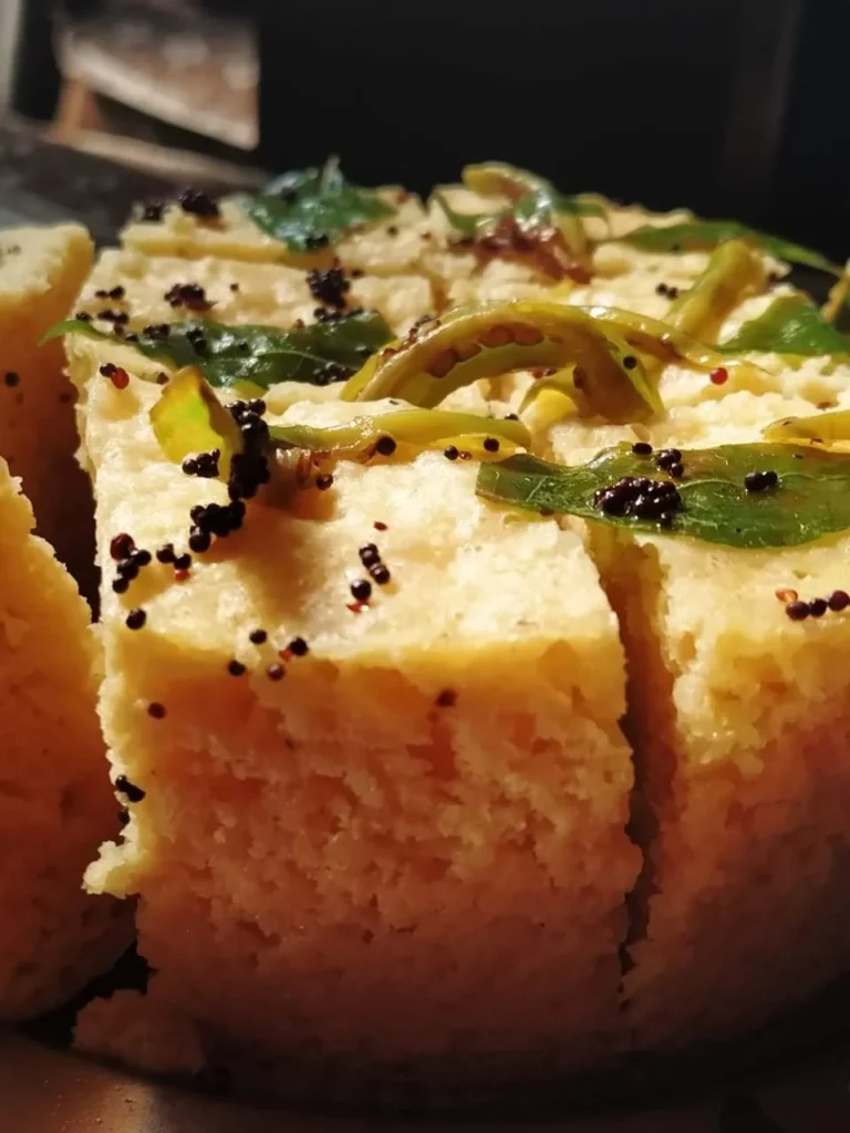 Sprinkling grated coconut and chopped coriander leaves over Dhokla