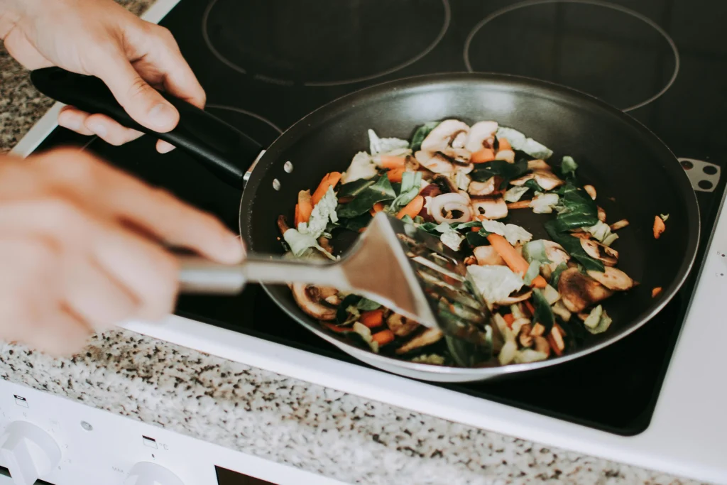 Person Frying Vegetables on a Pan