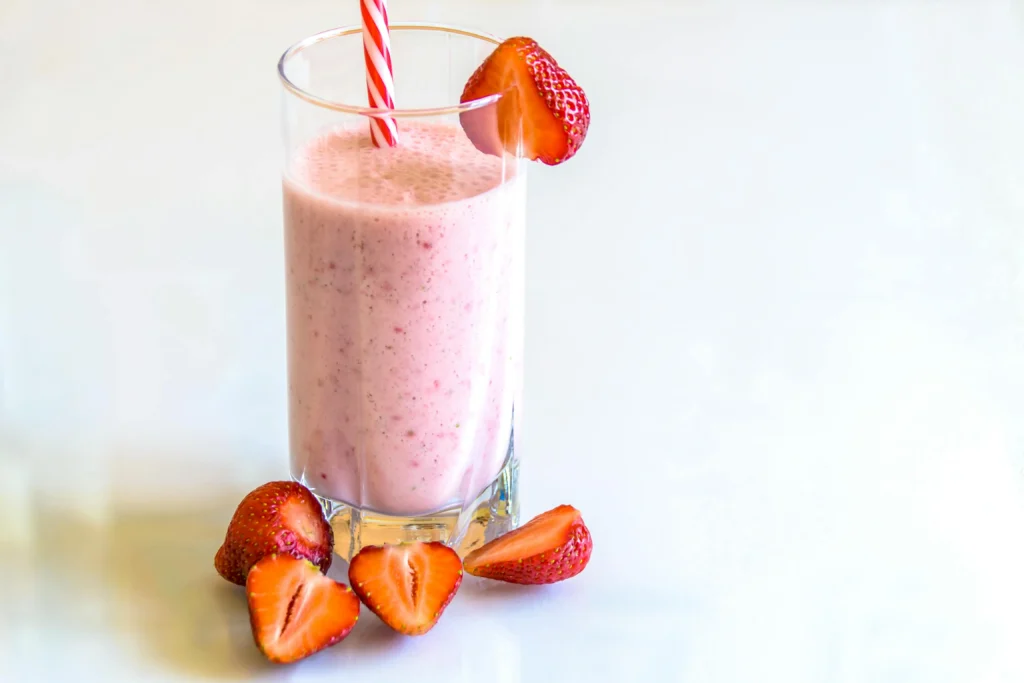 Picture of a glass pitcher filled with creamy pink Strawberry Horchata beverage