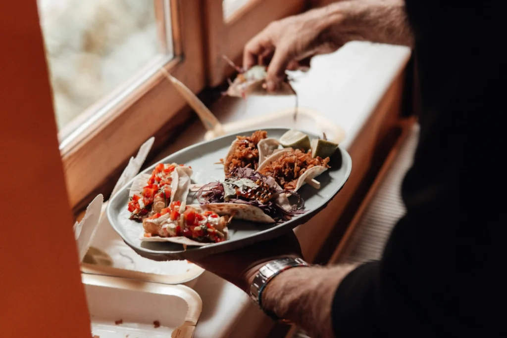 Unrecognizable male with plate with various tinga de pollo near containers