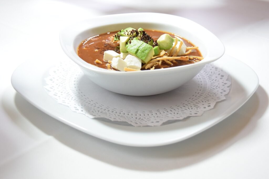 A steaming bowl of homemade tortilla soup served with lime wedges on the side.