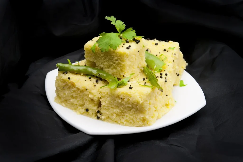 Dhokla squares neatly arranged on a serving plate, ready to eat