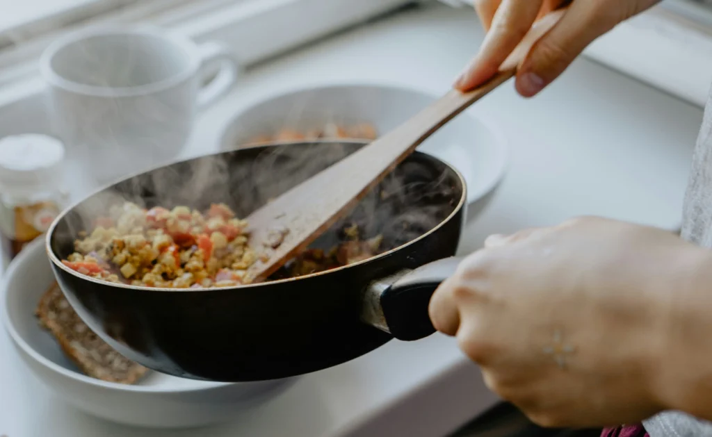 Melting cheese and sautéed vegetables in a skillet, ingredients for Queso Fundido preparation