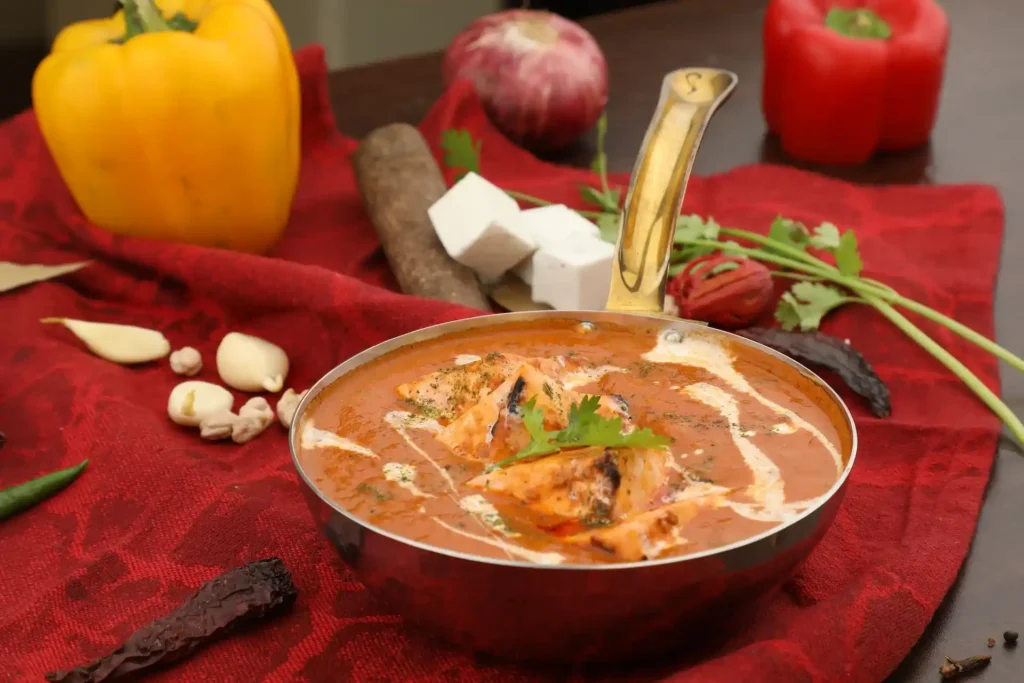 Fresh cream being stirred into Paneer Butter Masala for a rich and creamy texture