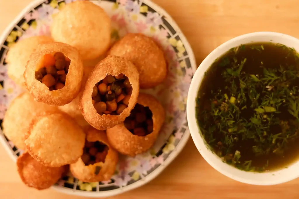 Pani Puri garnished with finely chopped onions, tomatoes, sev, and sweet tamarind chutney