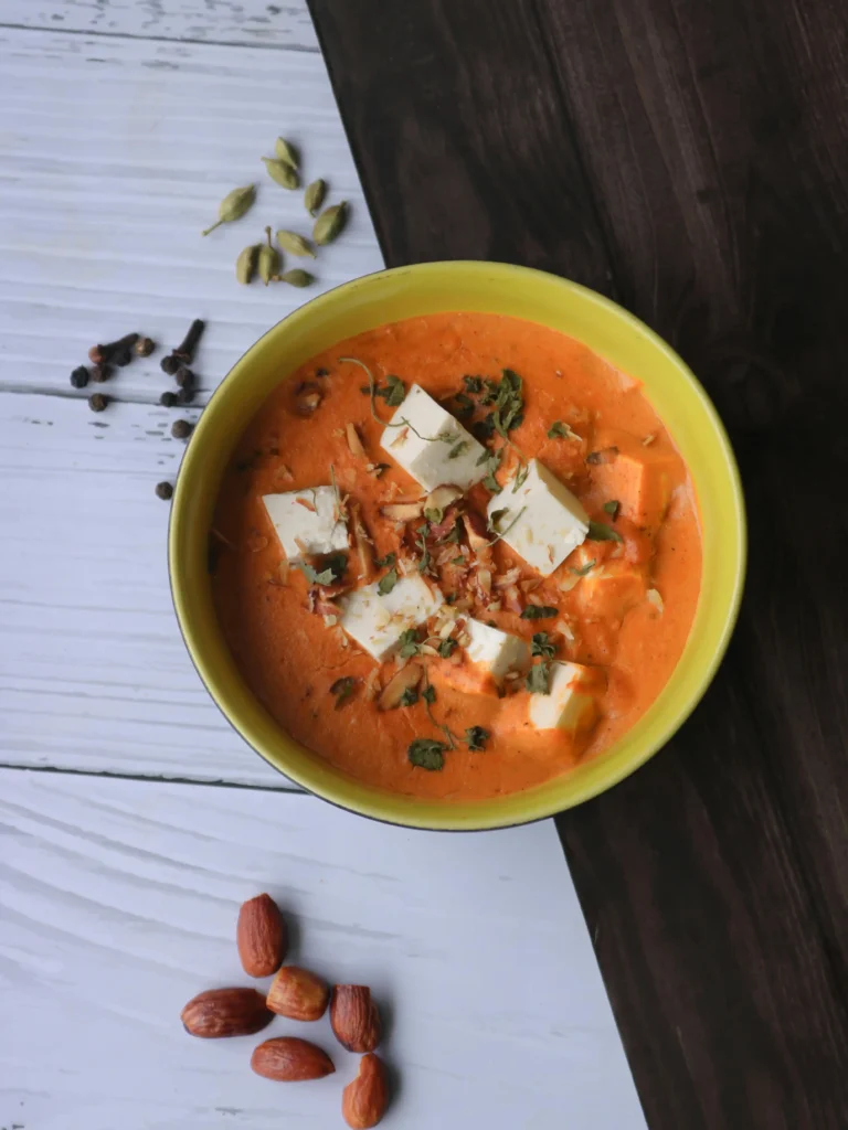 Paneer Butter Masala served with naan and a side of rice on a plate, ready to be enjoyed