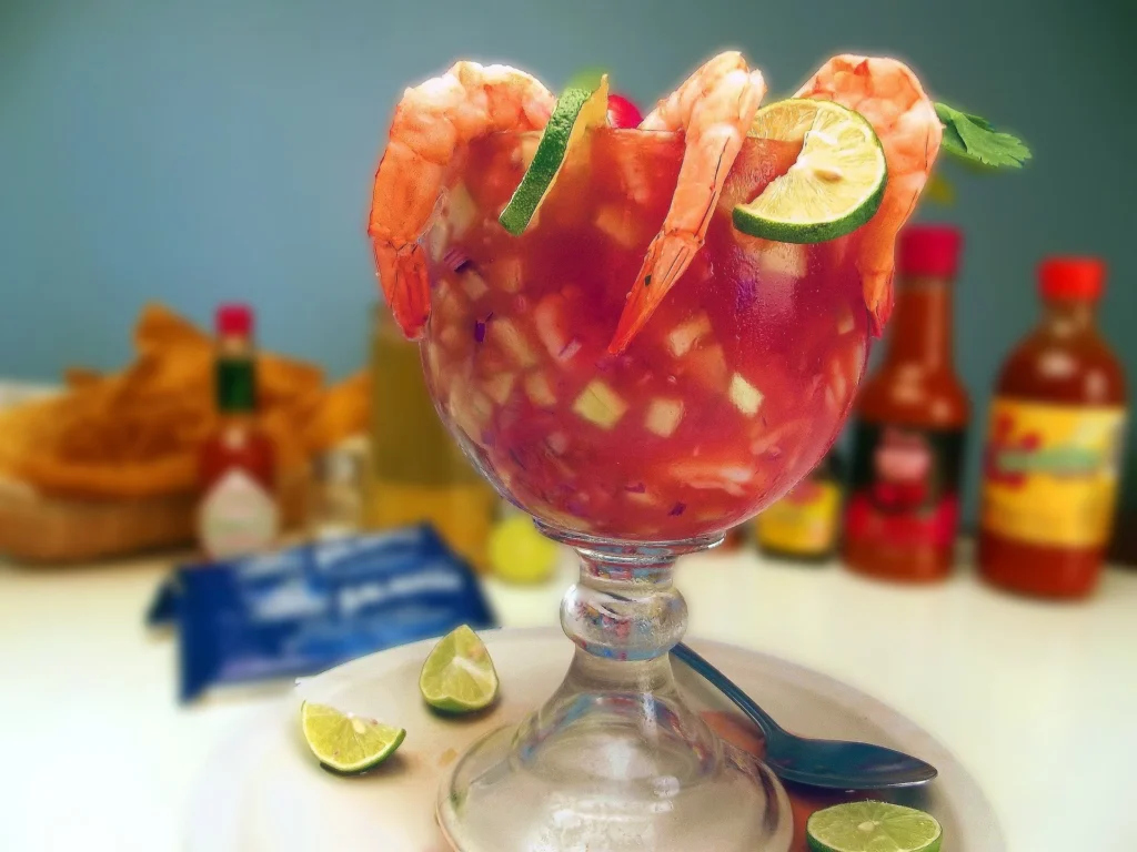 A serving of Mexican shrimp cocktail presented on a white plate with avocado slices