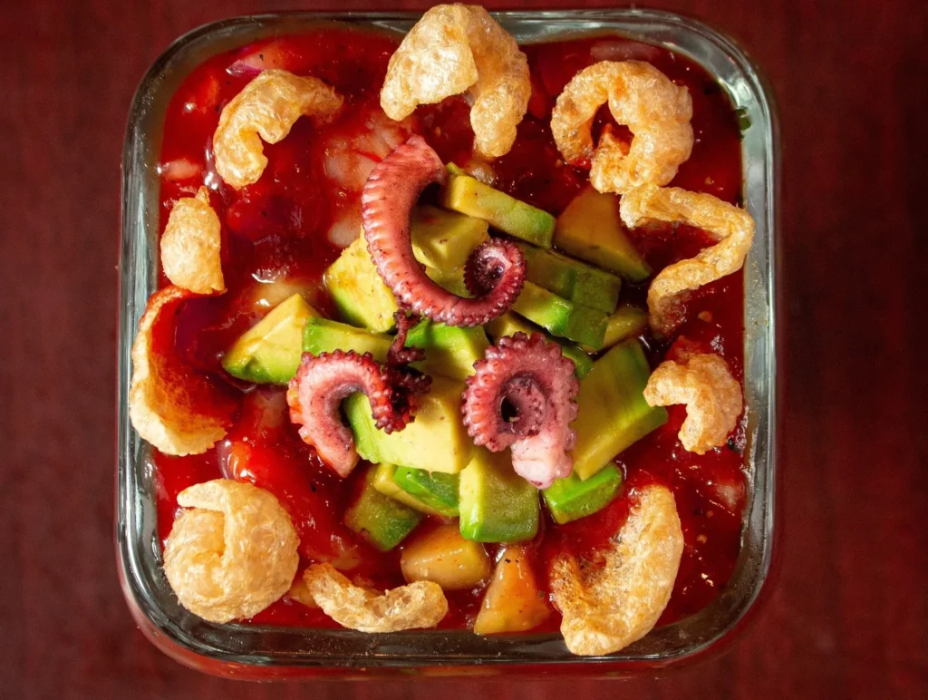 A bowl of Mexican shrimp cocktail with diced tomatoes, red onions, avocado, and cilantro