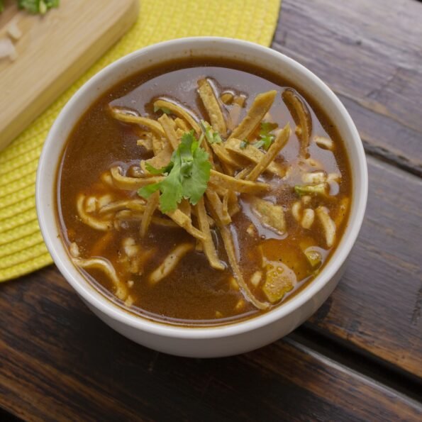 A bowl of sopa de tortilla made with vegetable broth and loaded with black beans and corn.