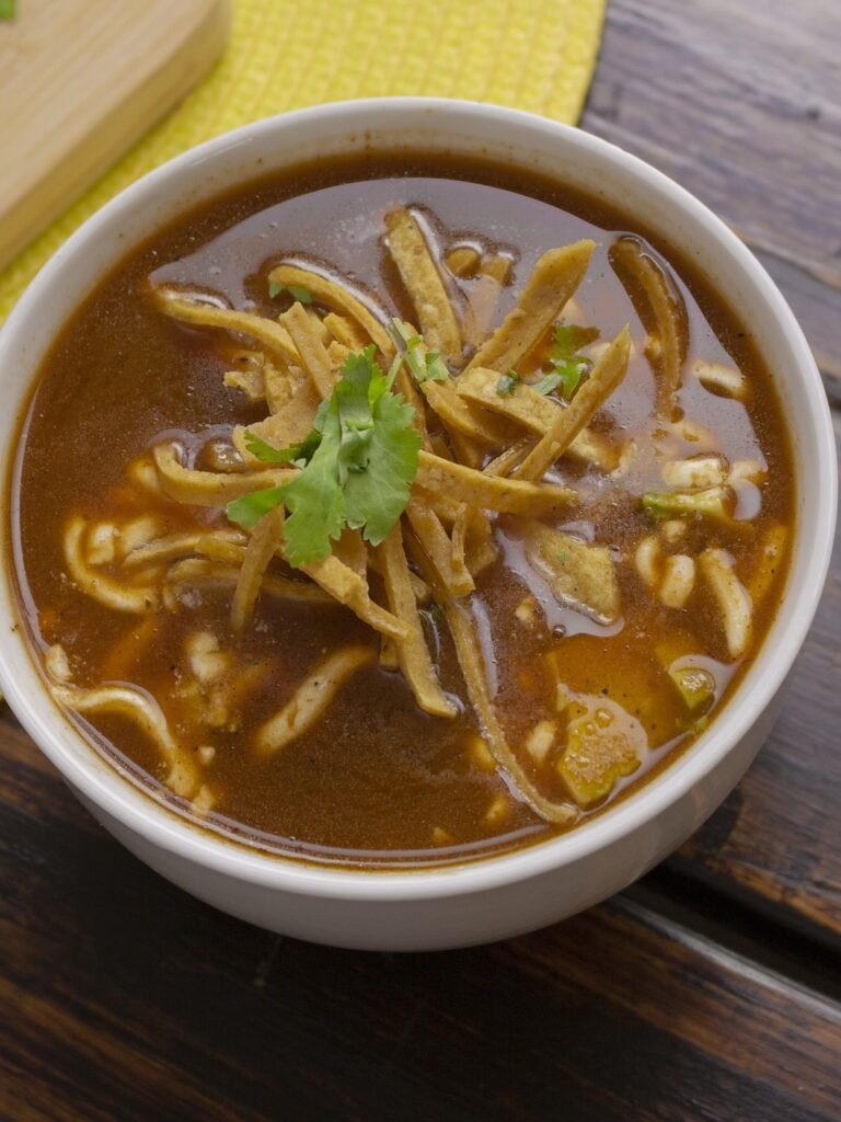 A bowl of sopa de tortilla made with vegetable broth and loaded with black beans and corn.