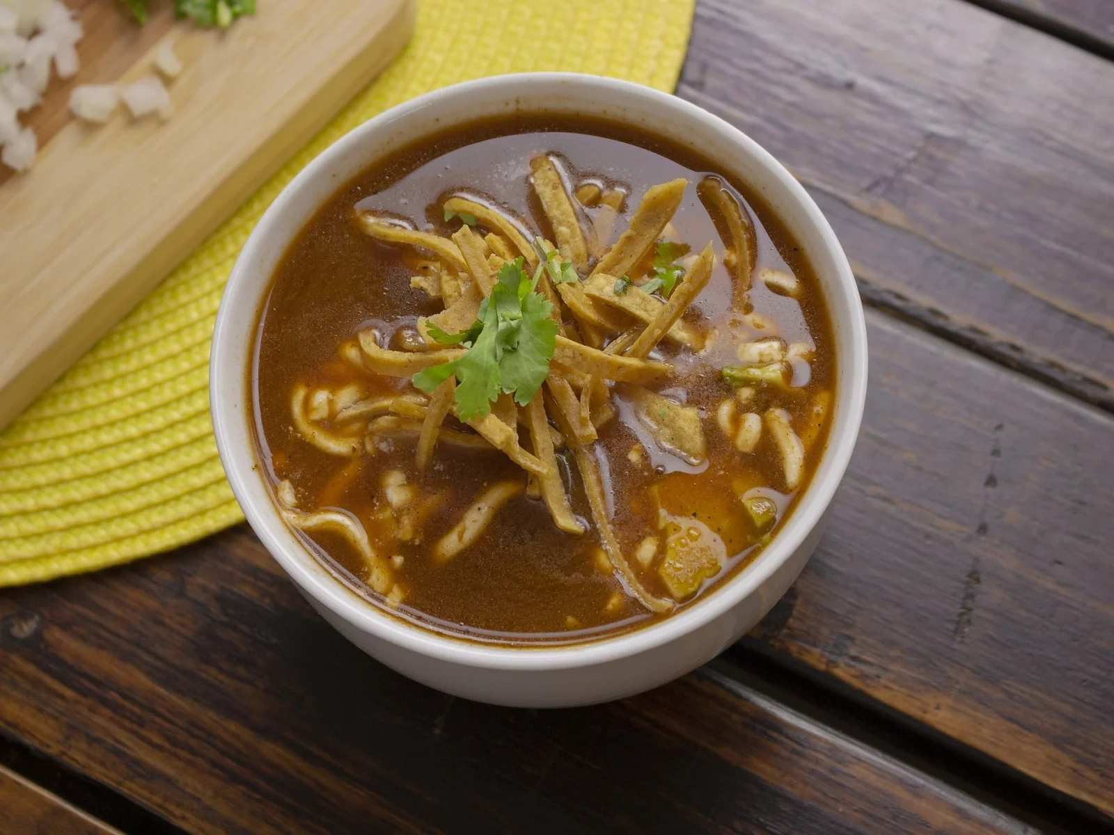 A bowl of sopa de tortilla made with vegetable broth and loaded with black beans and corn.