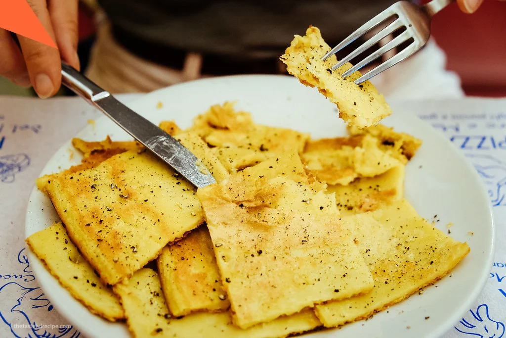 Farinata being sliced into portions, revealing its crispy exterior and tender interior