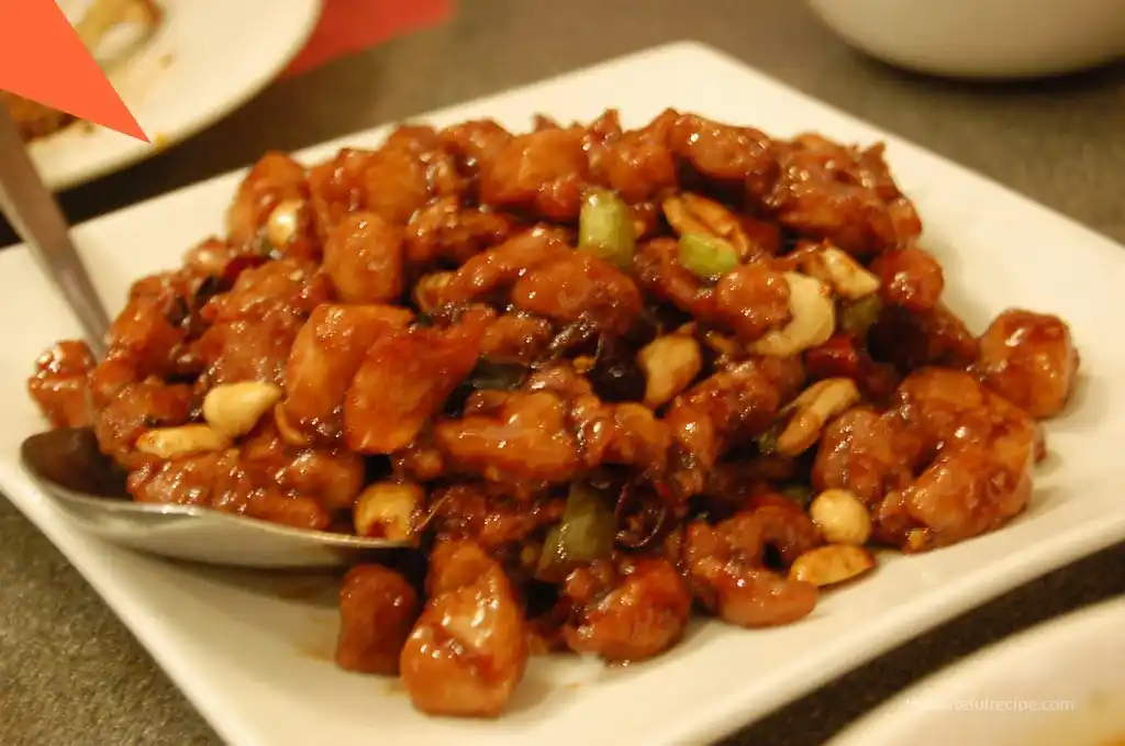 Stir-fried chicken being added back to the wok with cooked vegetables and sauce.