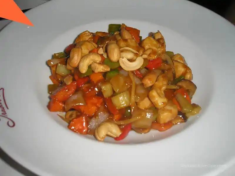 Kung Pao Chicken served on a white plate with a side of rice, ready to eat.