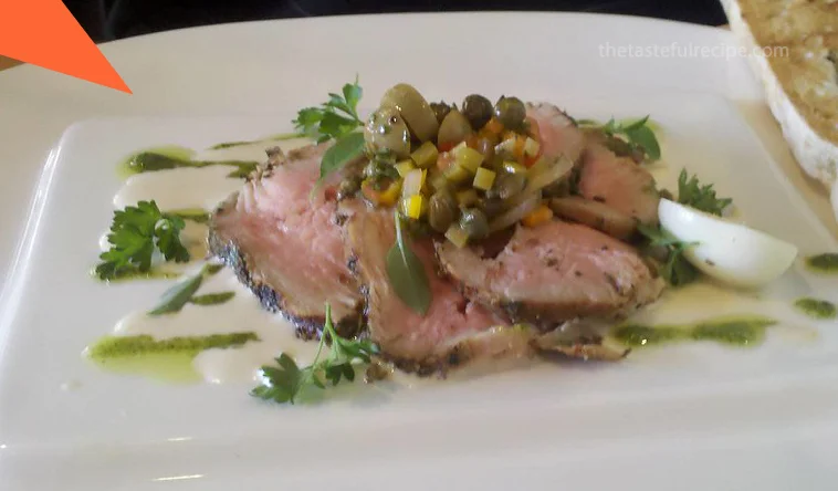 Creamy tuna sauce being poured over sliced veal