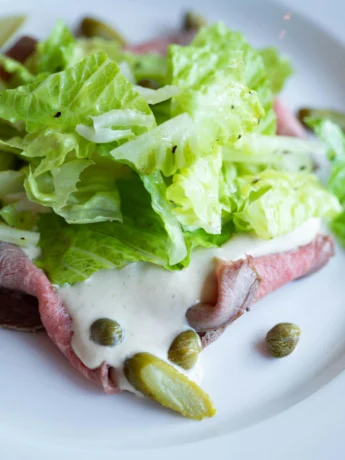 vitello tonnato served with sauce and lettuce