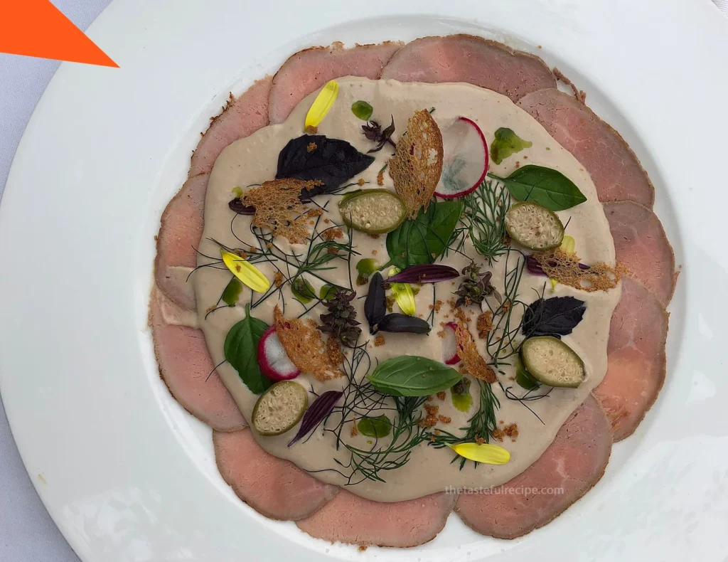 Beautifully presented Vitello Tonnato on a white plate, perfect for a summer meal or elegant appetizer