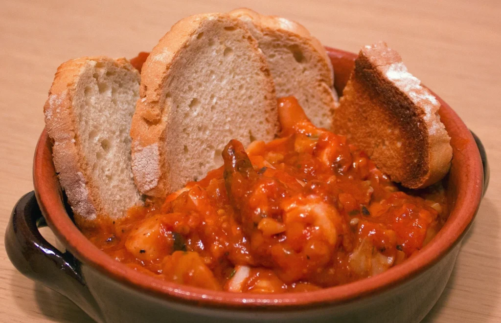 white fish in a tomato broth, garnished with fresh parsley and served with crusty bread.