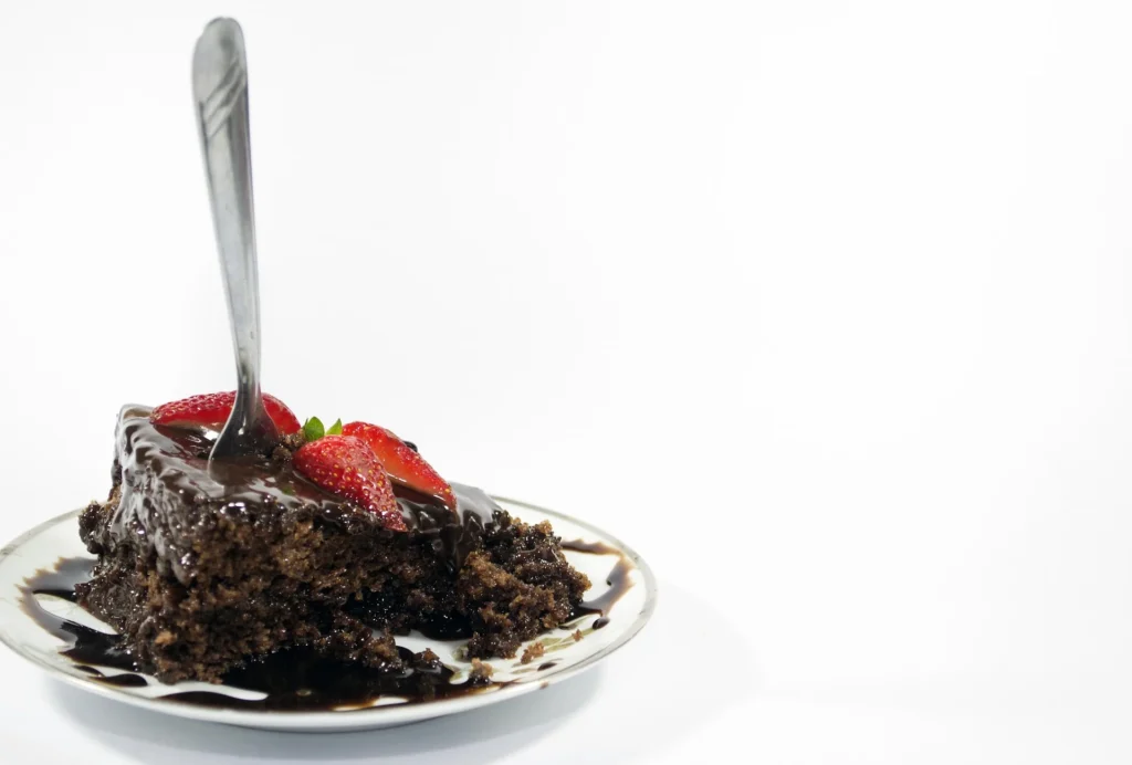 A slice of Torta Caprese served on a plate with a dollop of whipped cream and fresh berries