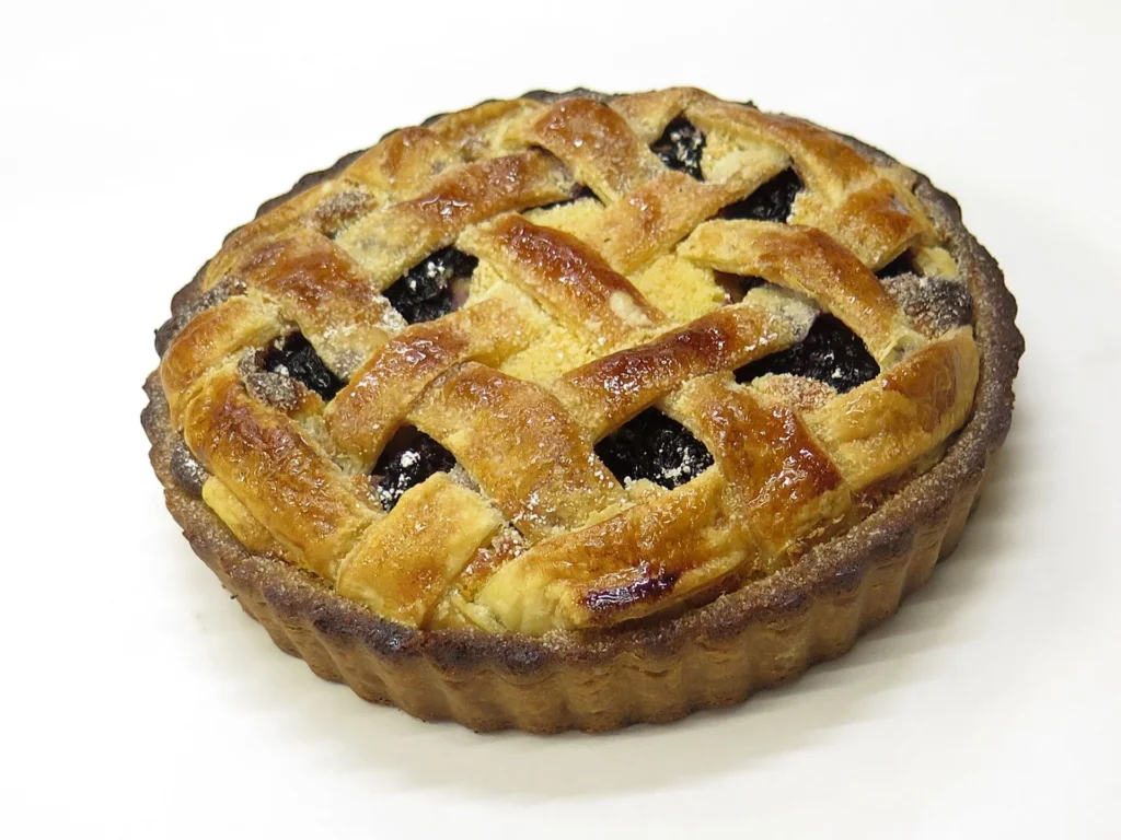 Serving a piece of Crostata on a plate, accompanied by a dollop of whipped cream