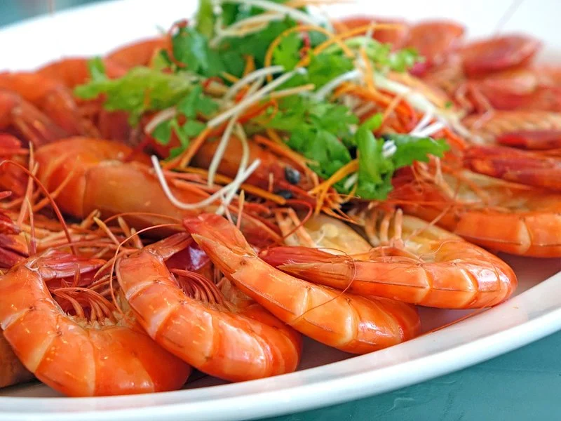 A close-up of a bowl of Cacciucco, garnished with chopped parsley, showing the vibrant colors of the seafood and tomato broth