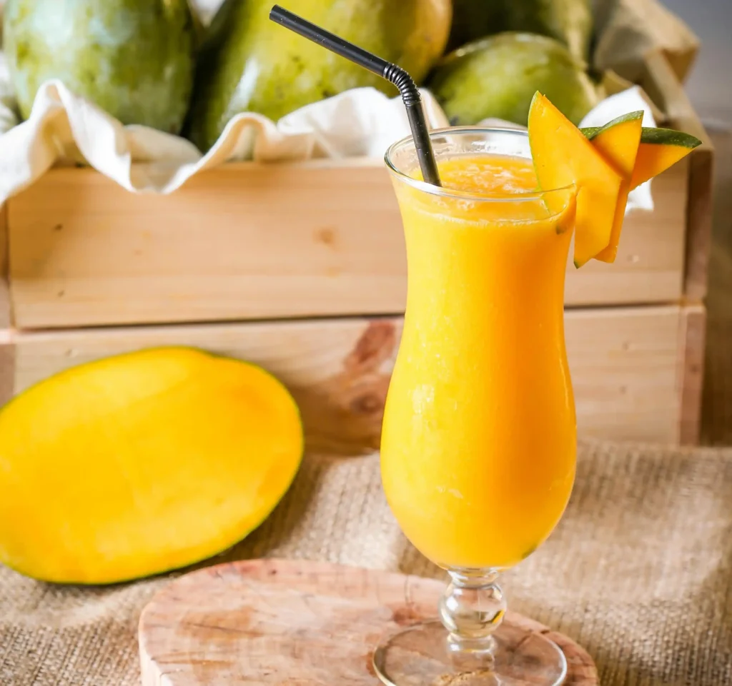 Clear Drinking Glass With Mango Smoothie and Sliced Fruit