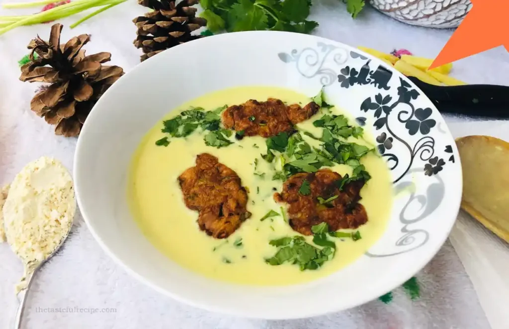 Bowl of Kadhi Pakora served with steamed rice and garnished with fresh coriander leaves