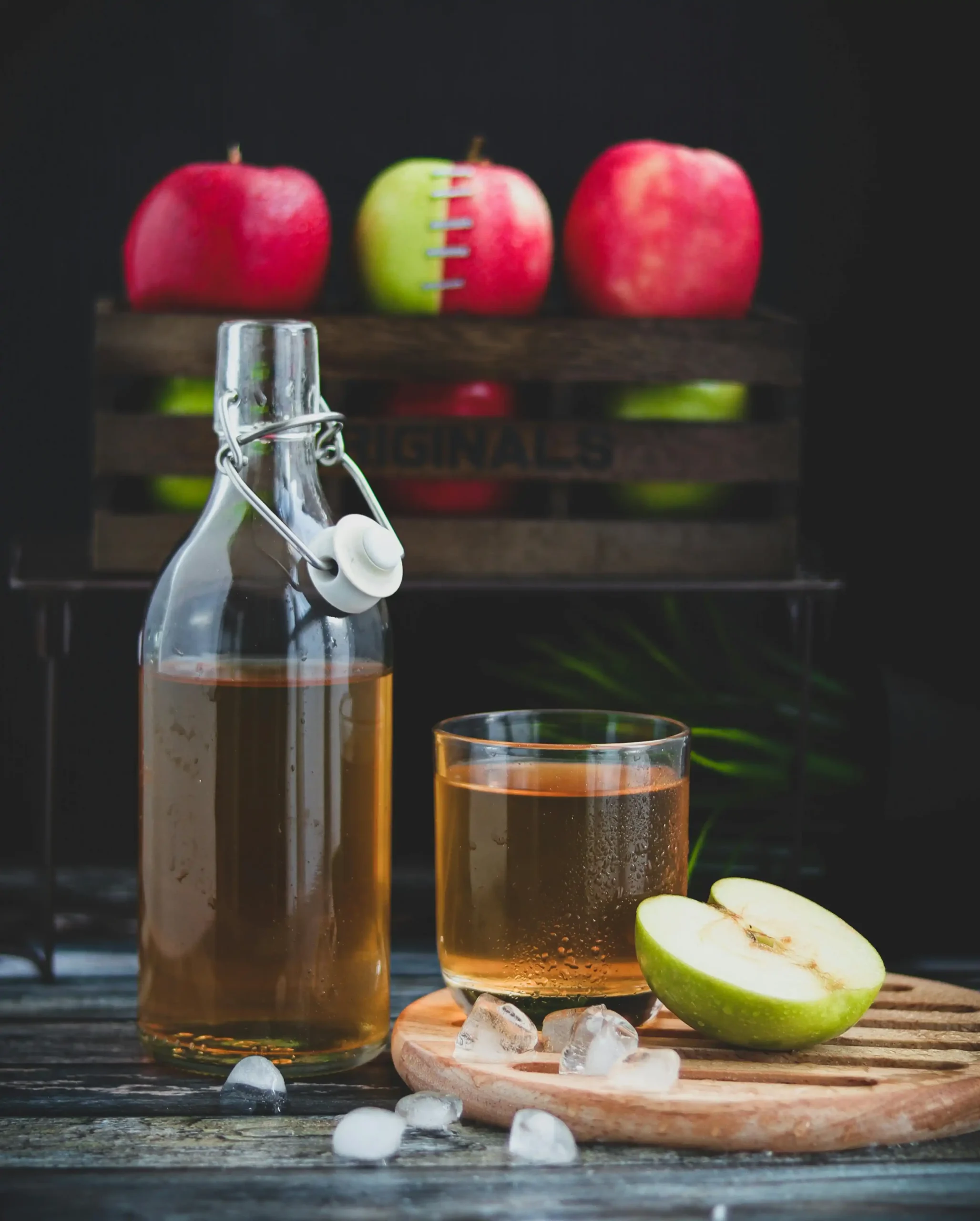 A Glass Bottle with apple cider vinegar Beside a Glass of apple cider vinegar